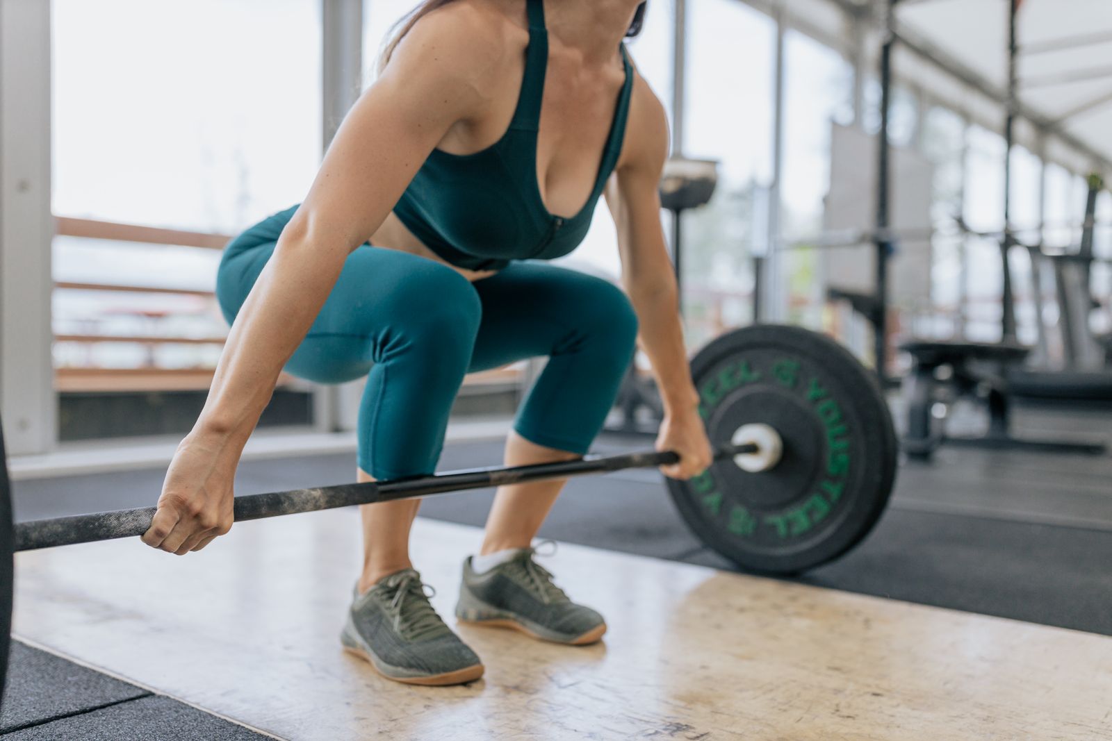 Adult woman strength training with a barbell in a gym